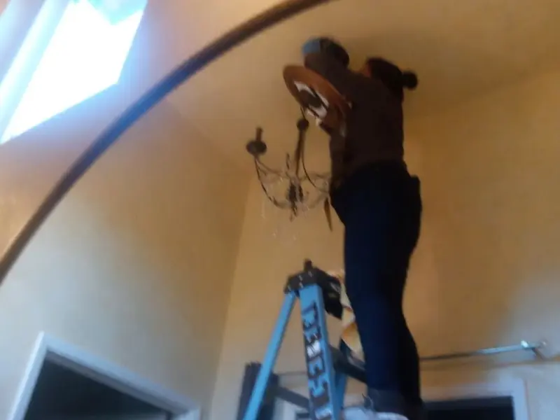 Electrician installing a chandelier in a Ridgway residence